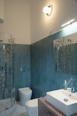 Une salle de bain avec une douche à parois de verre, des toilettes et un lavabo avec un miroir au-dessus.