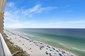 Een strand met rijen parasols en ligbedden, een heldere lucht en de oceaan.
