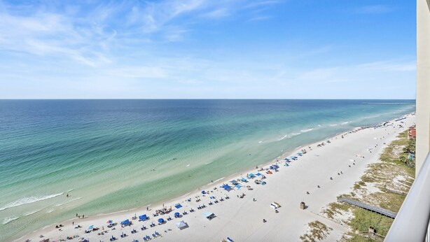 A beach with clear turquoise waters, a sandy shore, and a pier extending into the sea. - Majestic Beach Towers 1-1510 (Panama City Beach)