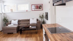 A modern living room with a brown leather sofa, a glass-top kitchen island, and a white refrigerator. - Seeidylle Winkler vacation apartment directly on Lake Ossiach with its own bathing beach (Bodensdorf)