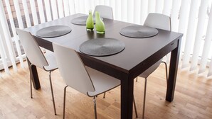 A dining table with four chairs, two green vases, and round placemats. - Seeidylle Winkler vacation apartment directly on Lake Ossiach with its own bathing beach (Bodensdorf)