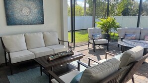 Un patio al aire libre con un sofá, sillas y una mesa.
