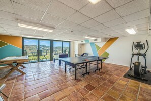 Una habitación amplia con mesa de ping pong, mesa de futbolín y cinta de correr.