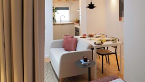 A cozy room with a bed, a small table with a cup, a chair, and a dining area with a table and chairs. - Elegant Studio with Terrace & AC by HostWise (Porto)