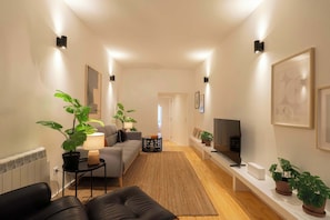 Ein modernes Wohnzimmer mit einer Couch, einem Couchtisch, einem Fernseher und Topfpflanzen.