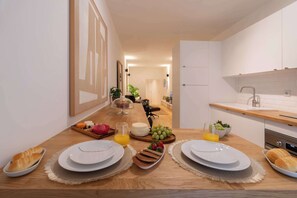 Eine moderne Küche mit weißen Schränken, einer Holz Arbeitsplatte und einem Essbereich mit gedecktem Tisch für das Frühstück.