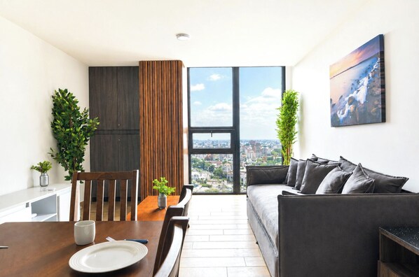 A modern living room with a dining area, large windows, and a city view. - Livo (Monterrey)