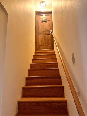 A wooden staircase with a handrail leading to a door with a sign above it. - Lake Waukewan Camp in Meredith (Meredith)