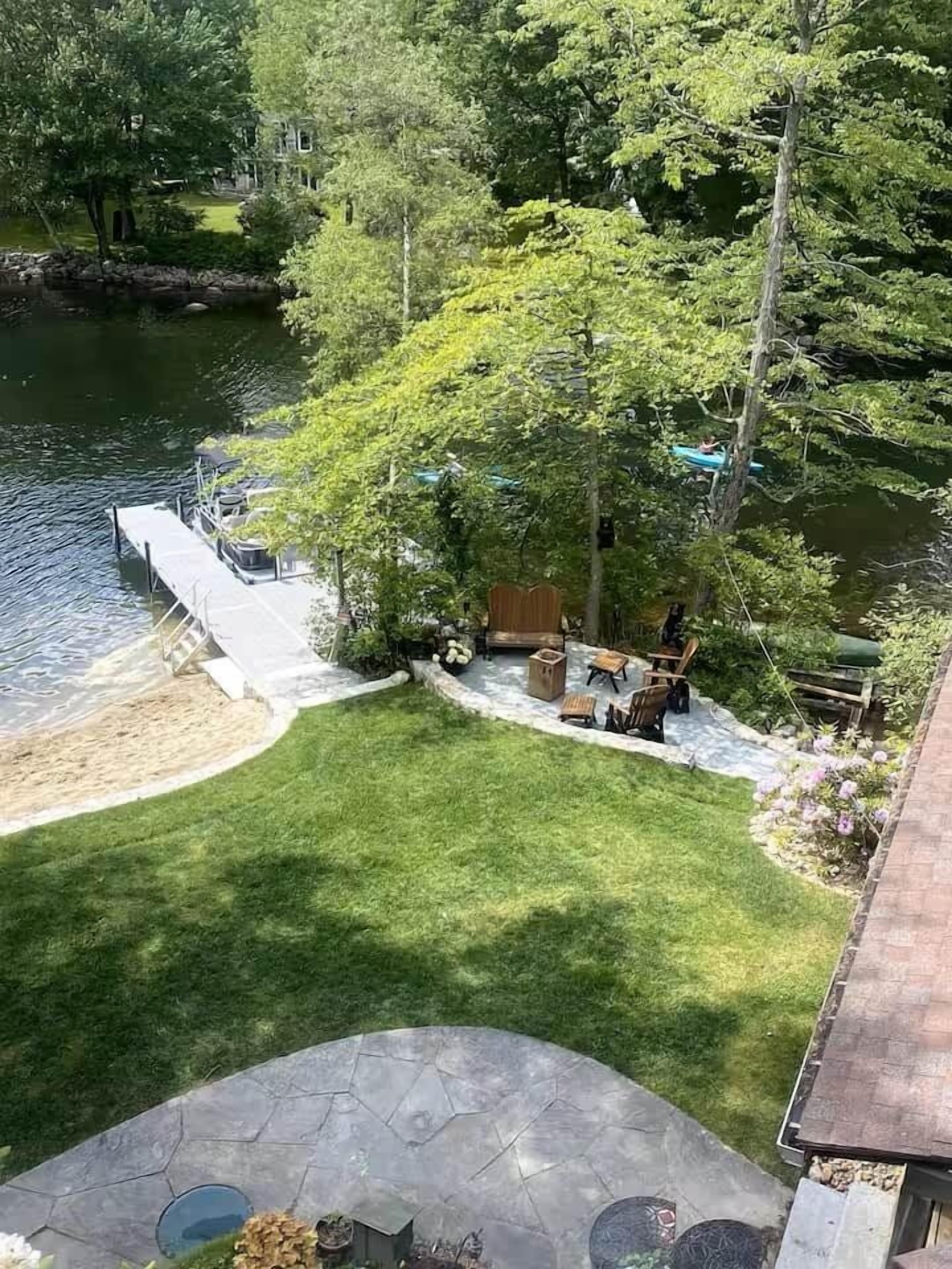 A view of a backyard with a patio, a small deck, and a grassy area.