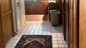 Una cocina con armarios de madera, un refrigerador, un lavamanos y un bote de basura.