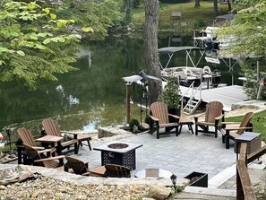 An outdoor patio with Adirondack chairs, a fire pit, and a dock extending into a lake. - Lake Waukewan Camp in Meredith (Meredith)