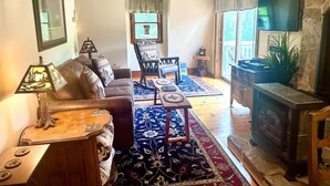 Una sala de estar con sofá, sillones, una mesita de centro, chimenea y televisor.