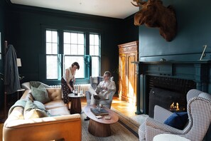 Una habitación con chimenea, muebles de cuero y una cabeza de animal montada.