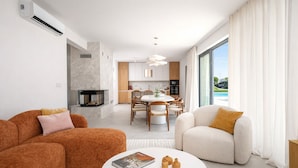 A modern living room with a fireplace, a dining area, and a large window with a view. - Designer Beach Villa Limes - Pool, Spa & Games (Funtana)