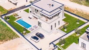 A modern two-story house with a rooftop pool, a covered patio, and a driveway with two cars. - Designer Beach Villa Limes - Pool, Spa & Games (Funtana)