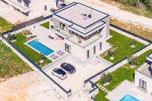 A modern two-story house with a rooftop pool, a covered patio, and a driveway with two cars. - Designer Beach Villa Limes - Pool, Spa & Games (Funtana)