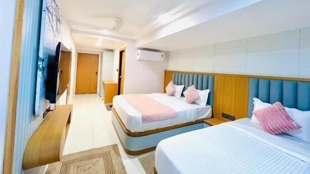Ein Hotelzimmer mit zwei Betten, einem Fernseher und einem Deckenventilator.