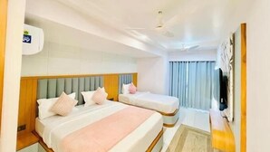 Ein Hotelzimmer mit zwei Betten, einem Deckenventilator und einem großen Fenster mit Vorhängen.