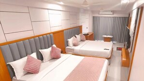 Ein Hotelzimmer mit zwei Betten, jeweils mit einem Holz-Kopfteil, einem Nachttisch und einem kleinen Tisch mit einer Lampe.
