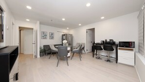 Una cocina moderna con zona de comedor, que incluye un refrigerador, microondas y taburetes de bar.