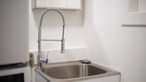 Una cocina moderna con un lavamanos de acero inoxidable, un grifo flexible y un armario blanco arriba.