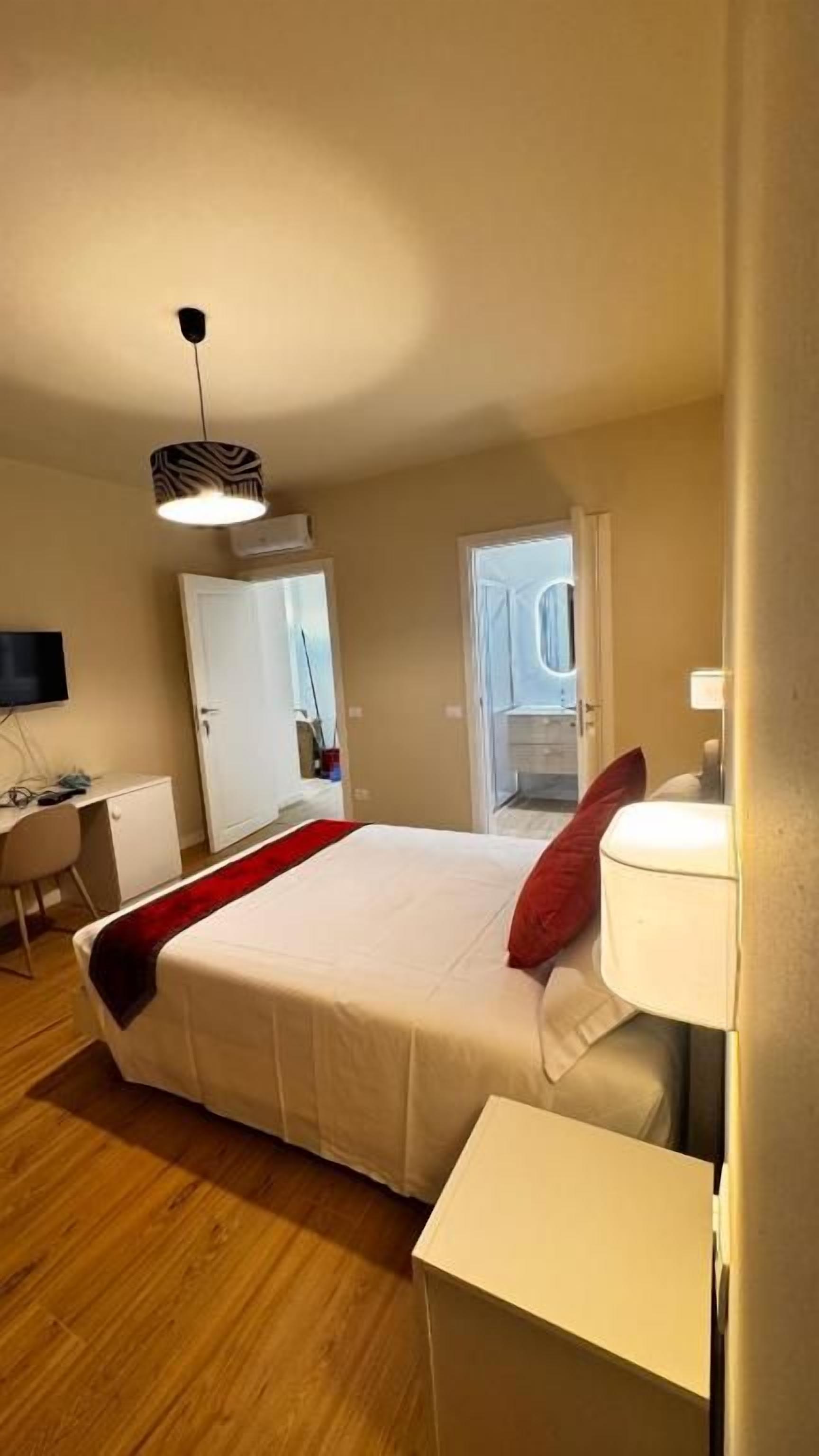 A bedroom with a bed, bedside table, and a desk with a chair.