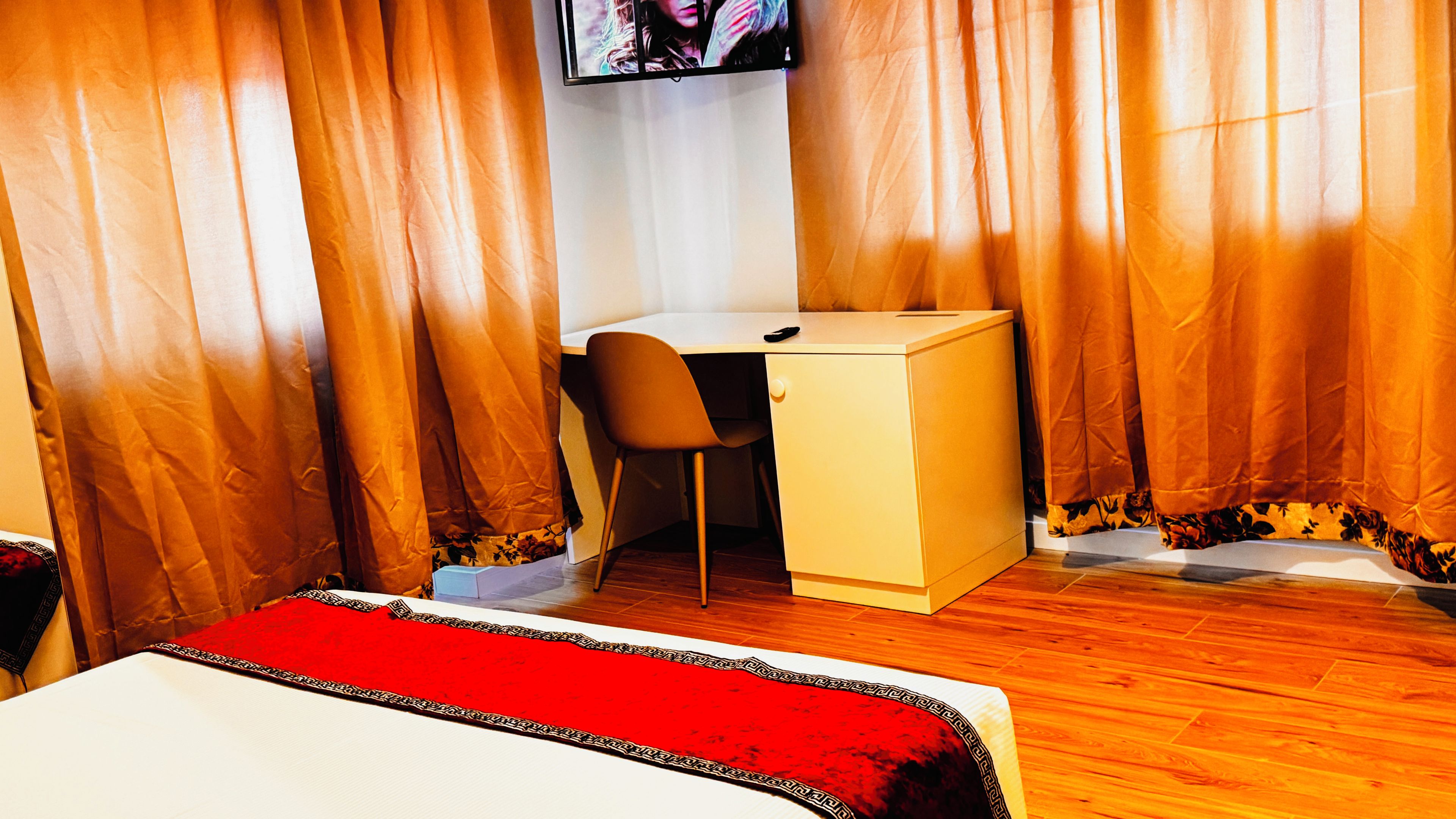 Una habitación de hotel con cama, escritorio, silla y cortinas.