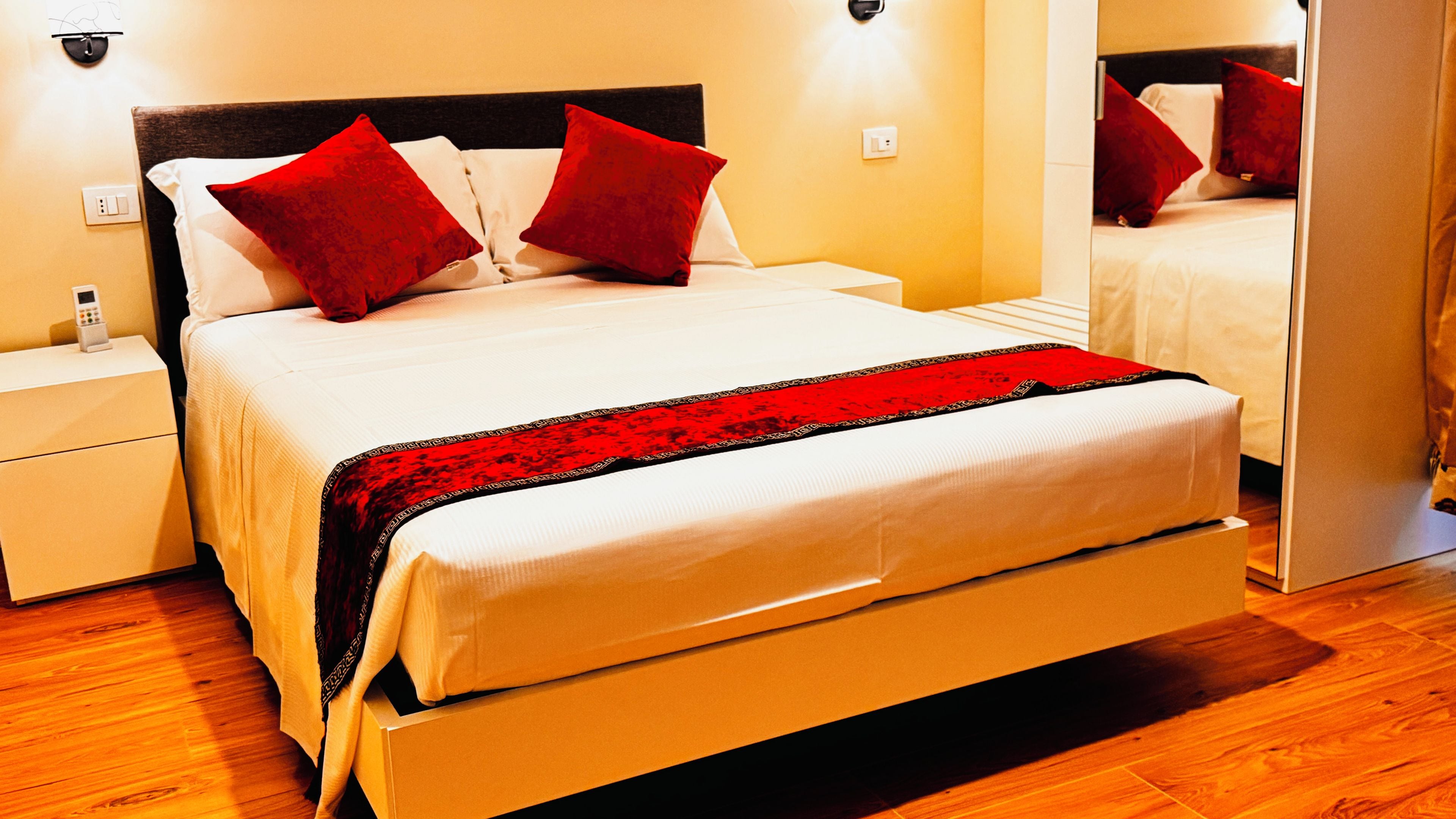 Una habitación de hotel con cama, mesitas de noche y un espejo.
