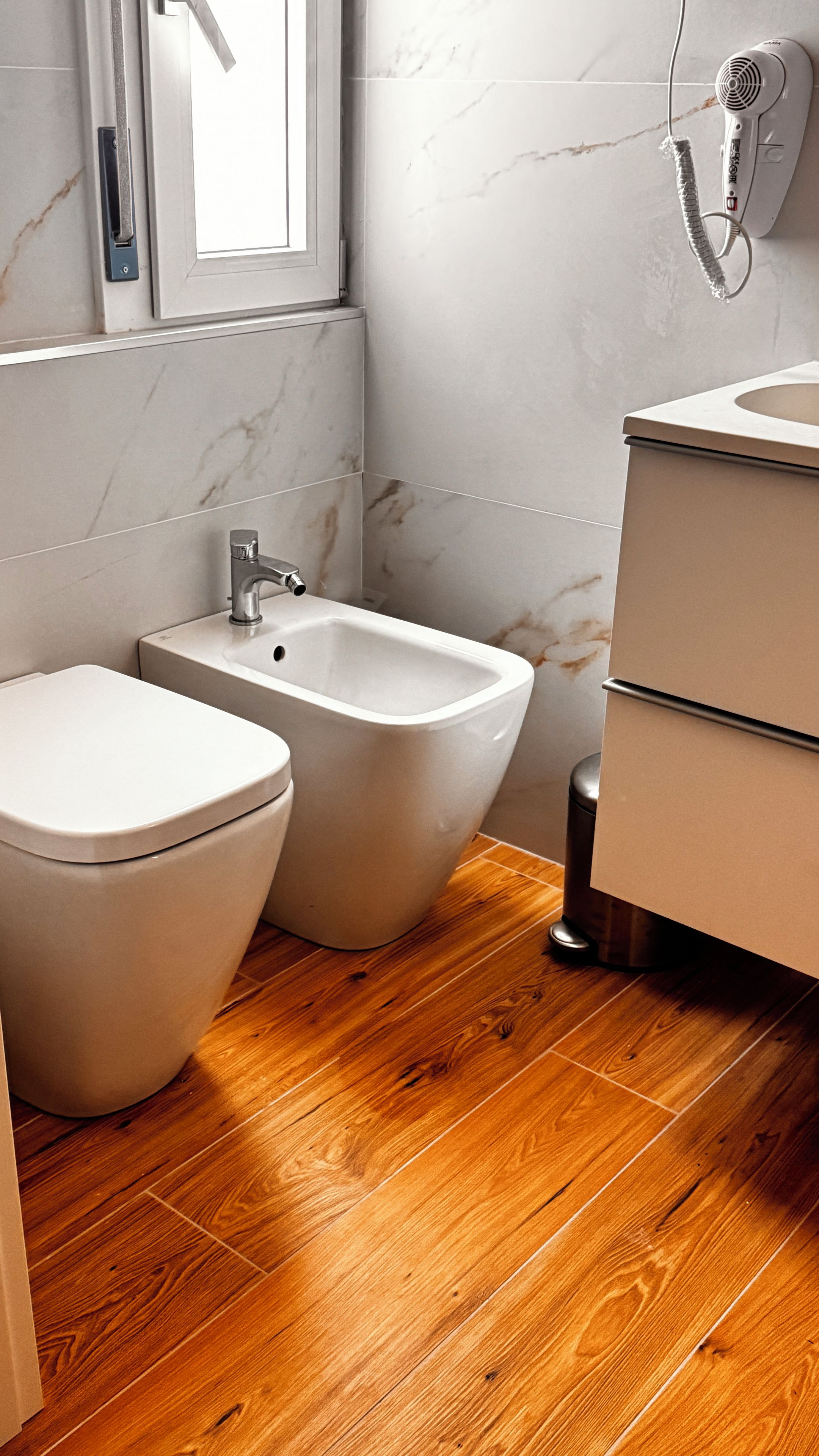 Un baño moderno con un bidé, un inodoro y un lavamanos.