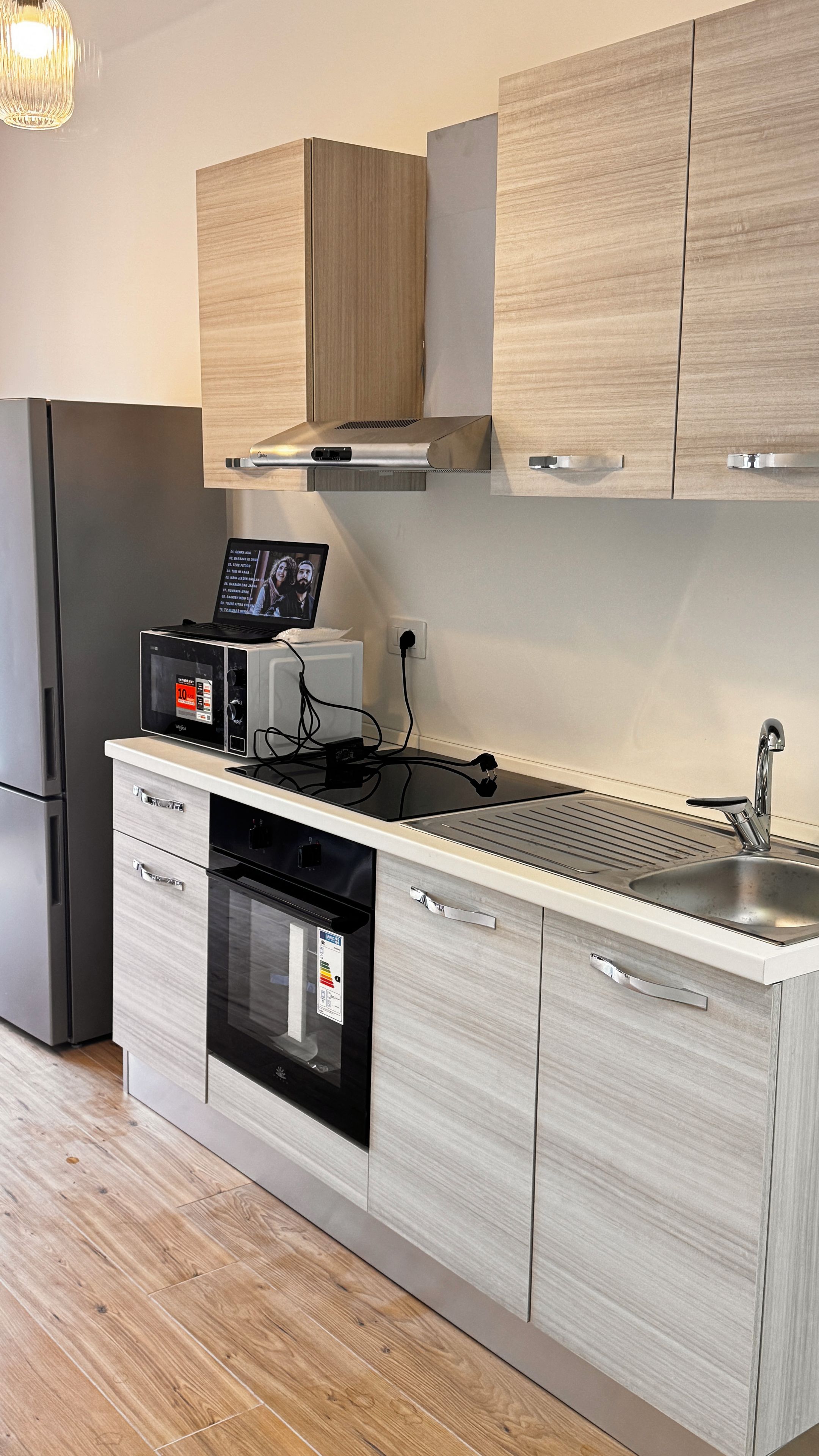 Una cocina moderna con horno integrado, microondas y pileta de acero inoxidable.