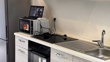 Una cocina moderna con horno integrado, microondas y pileta de acero inoxidable.