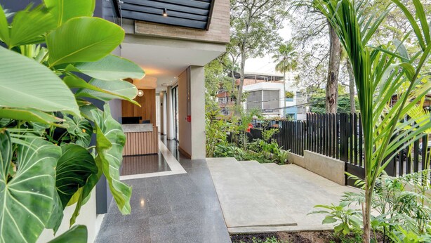 A modern building with a covered entrance, a concrete pathway, and lush greenery. - Deluxe 2-bed  Walk to Cali's Best Dining 103 (Cali)