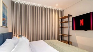 A hotel room with a bed, a TV mounted on the wall, and a window with curtains. - Deluxe 2-bed  Walk to Cali's Best Dining 103 (Cali)