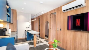 A modern hotel room with a kitchen area, a flat-screen TV, and a seating area with a sofa and a coffee table. - Deluxe 2-bed  Walk to Cali's Best Dining 103 (Cali)