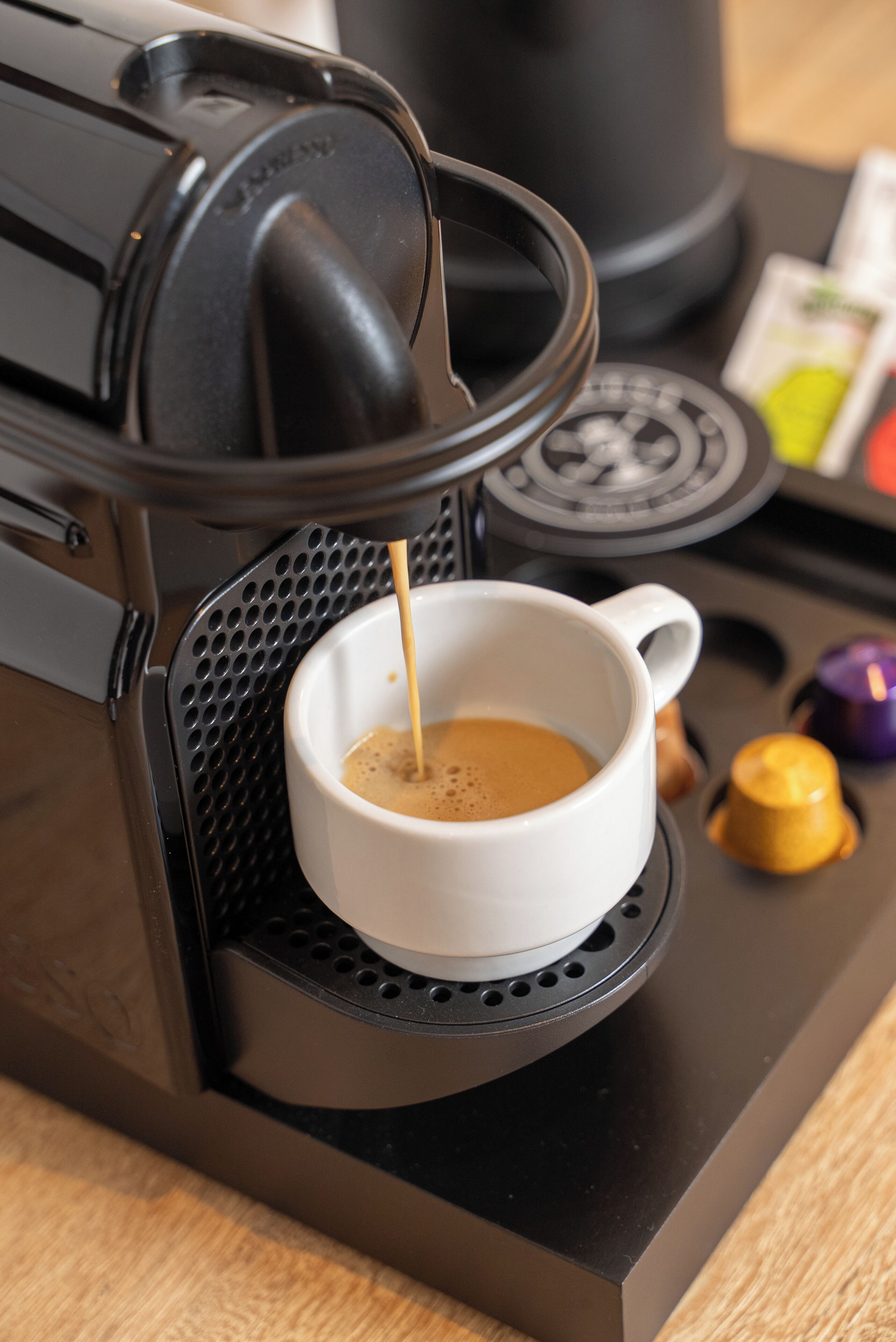 A coffee machine with a cup of coffee being dispensed into it.