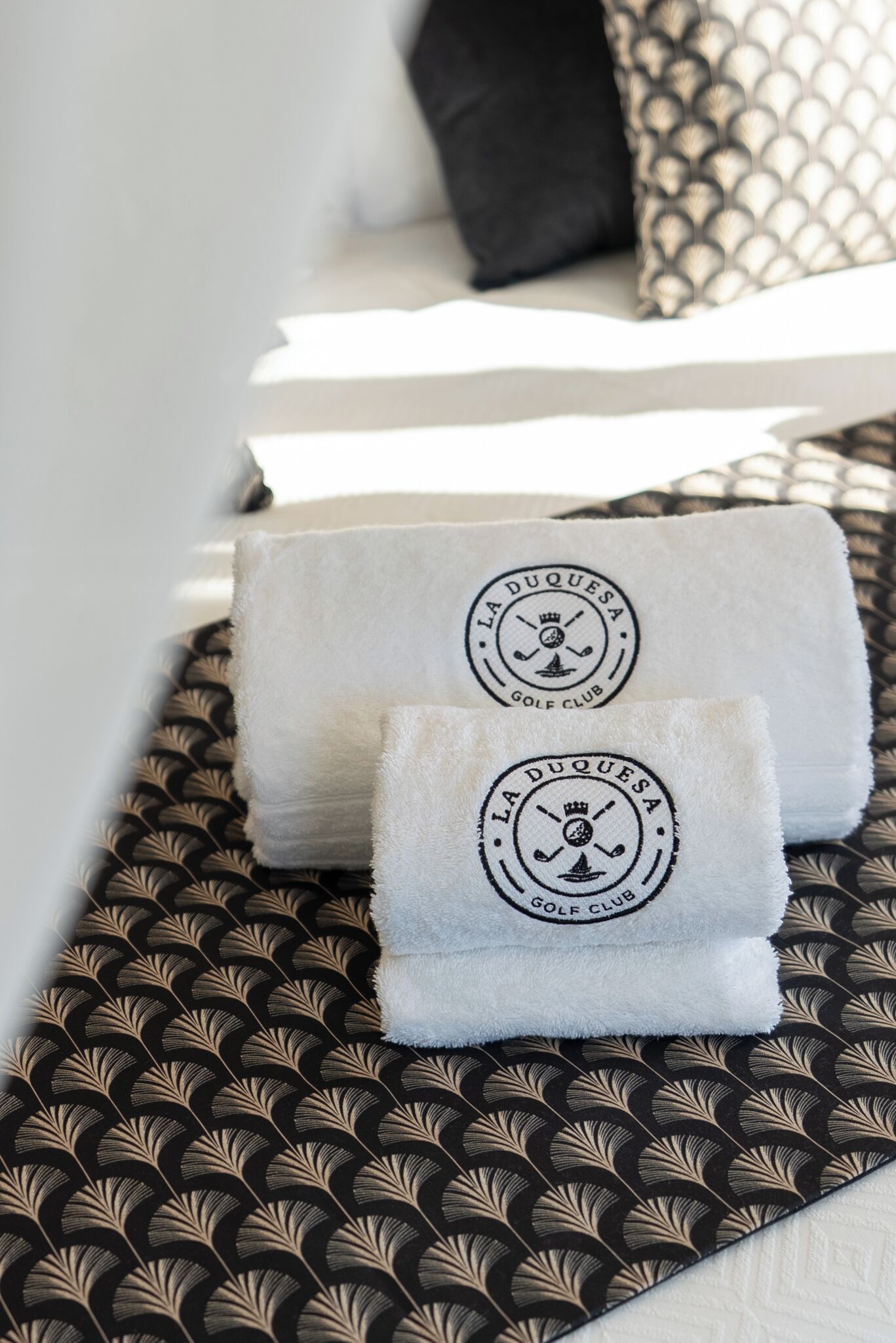 Two towels with a logo on a patterned bedspread.