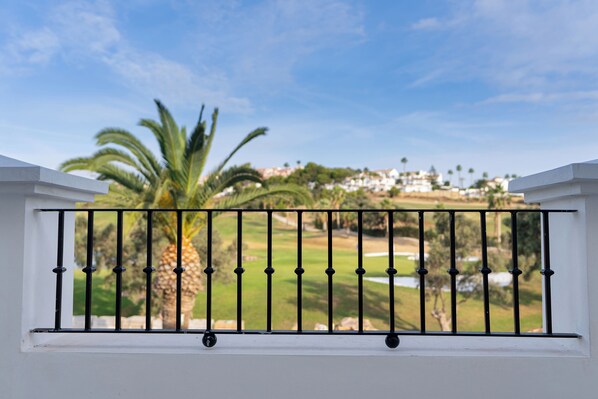 A balcony with a metal railing overlooking a golf course and residential buildings. - Duquesa Golf Club (Manilva)