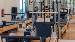 A Pilates studio with equipment and mats arranged in rows.
