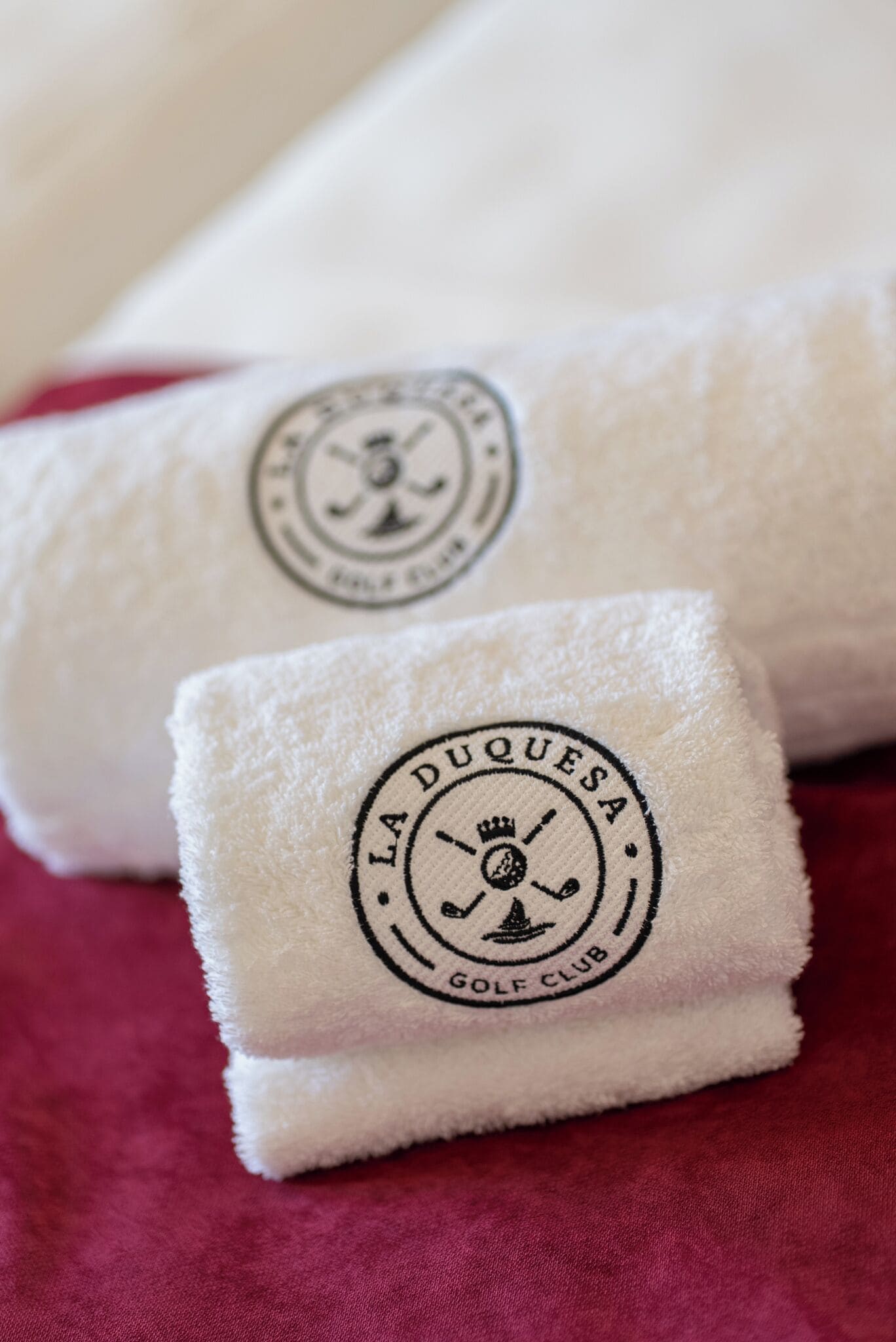 Twee gevouwen handdoeken met een logo en tekst die aangeeft dat ze van La Duquesa Golf Club zijn.