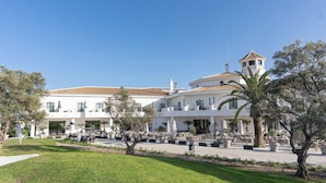 A large building with a white facade, multiple balconies, and a tiled roof.