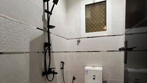Une salle de bain avec des toilettes, une douche et une fenêtre.