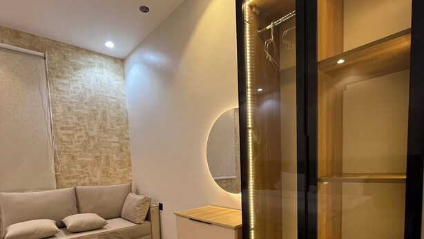 Un salon moderne avec un canapé, une table basse et un meuble vitré doté de lumières LED.