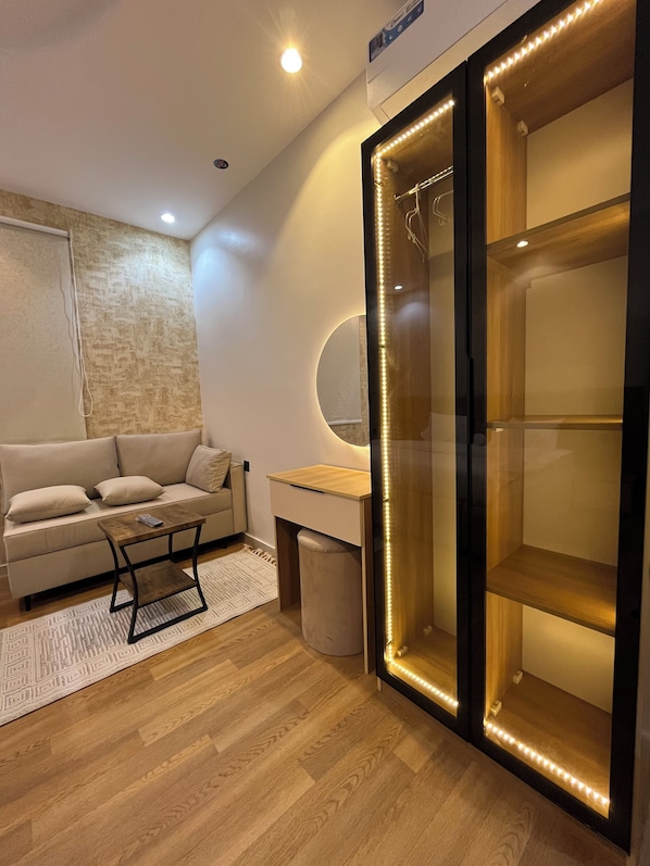 A modern living room with a sofa, coffee table, and a glass-enclosed cabinet with LED lights. - M4-101 (Madinah)