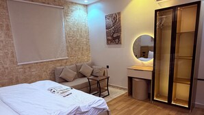 Une chambre moderne avec un grand lit, un bureau, une chaise, une armoire et un miroir fixé au mur.