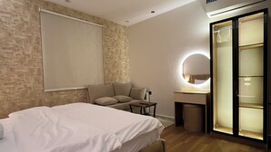 Une chambre moderne avec un grand lit, un bureau avec une lampe, une armoire et un luminaire circulaire au plafond.