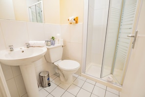 A bathroom with a sink, toilet, and glass shower enclosure.