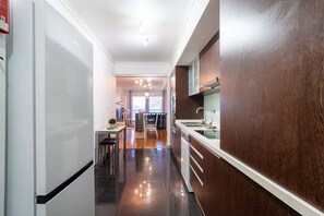 A modern kitchen with dark wood cabinetry, a white countertop, and a stainless steel sink. - GuestReady - Serenity retreat in Caniço (Caniço)