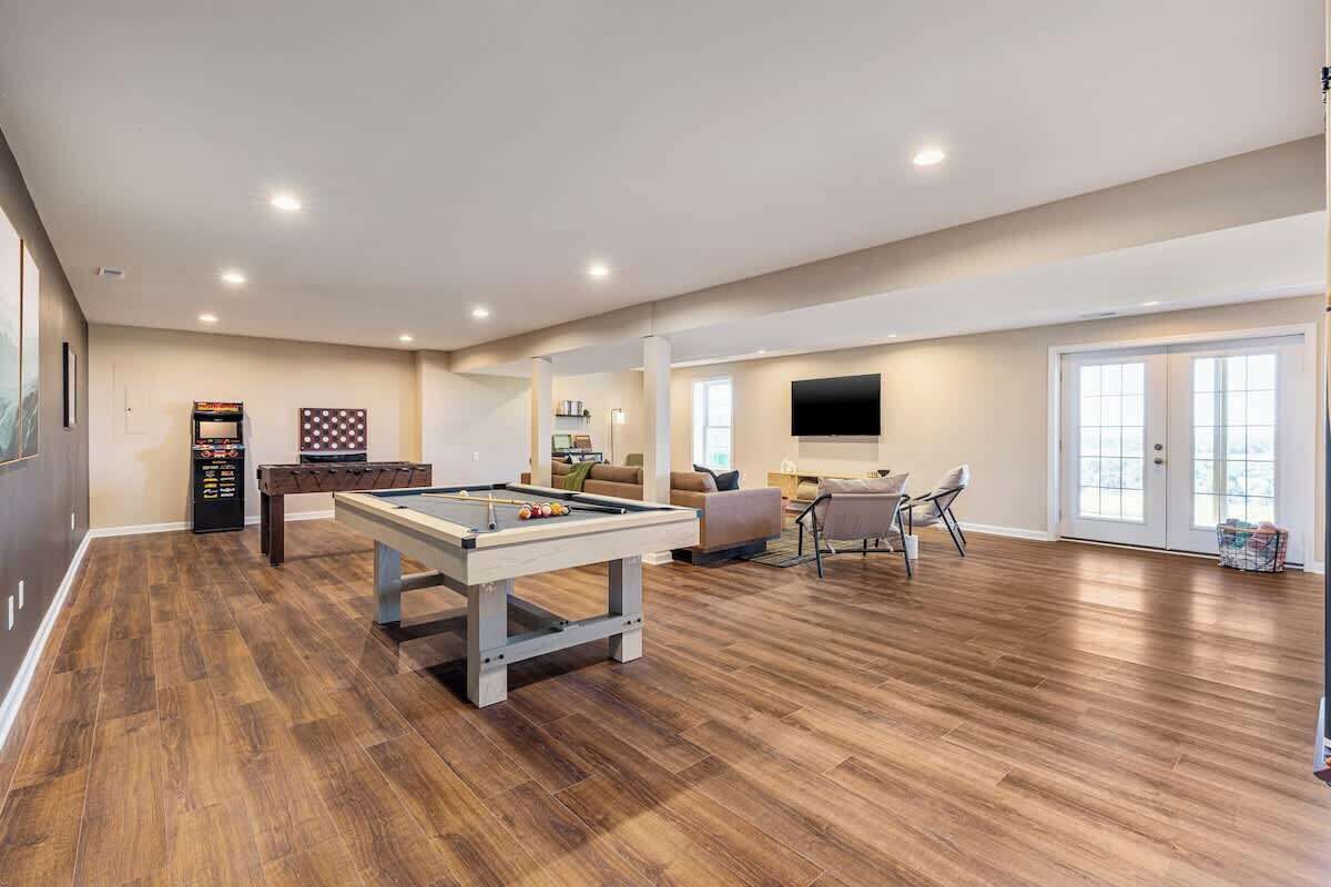 A spacious indoor area with a pool table, a sofa, and a television.