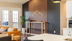 A modern living room with a sofa, a coffee table, a dining table, and a potted plant. - Luxury Mountain Retreat w/ Valley Views, Hot Tub (Front Royal)