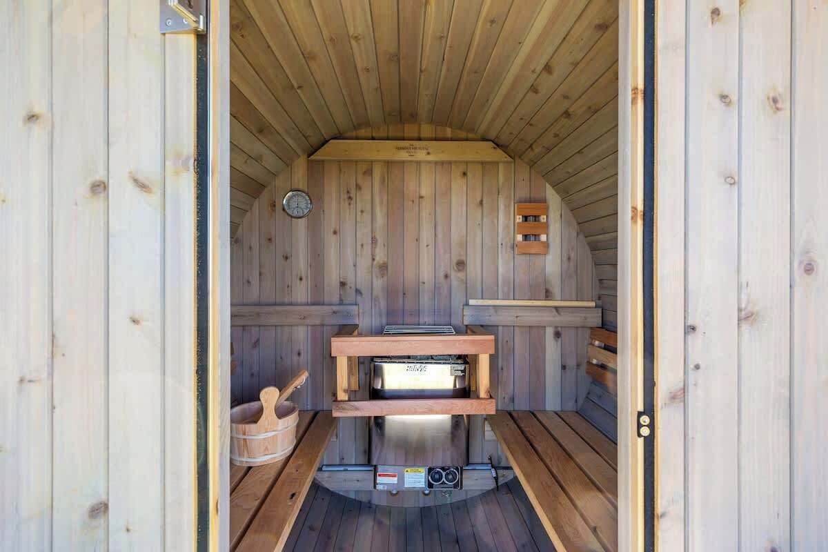 A sauna with wooden walls, a bench, and a control panel.